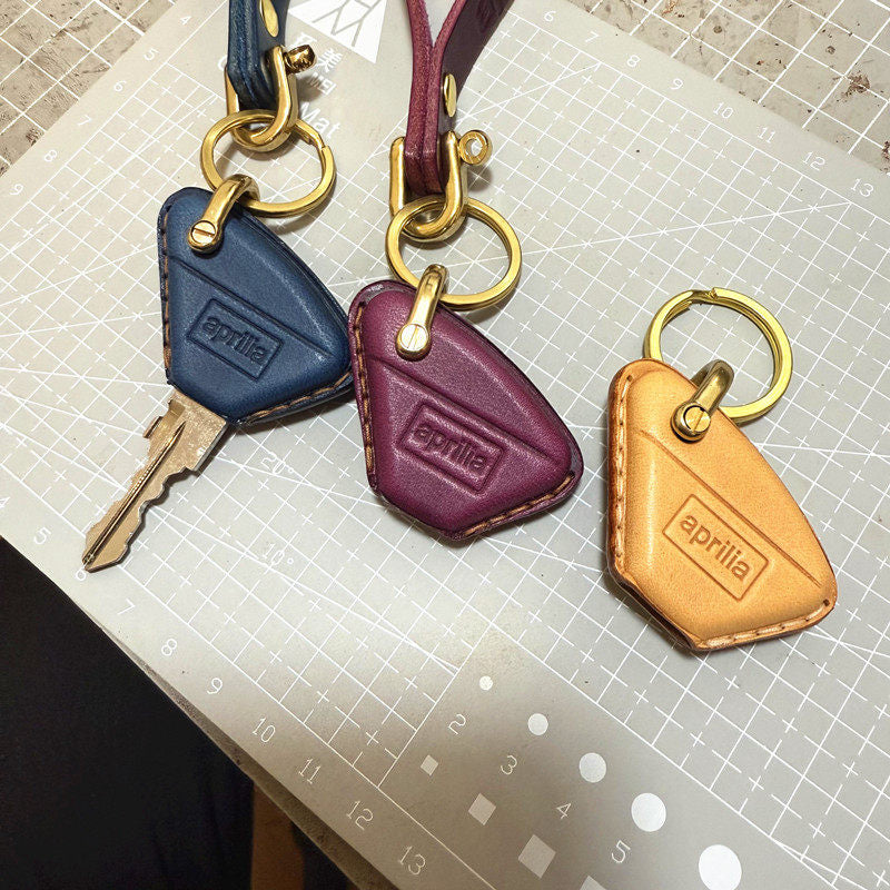Handmade leather key case for Aprilia RS457 in navy, burgundy and tan with brass keyring
