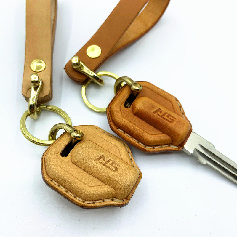Close-up of embossed SYM logo and hand stitching on leather key case